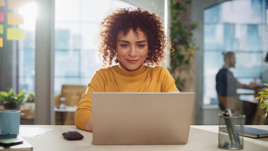 A woman smiling as she completes the online questionnaire on a laptop