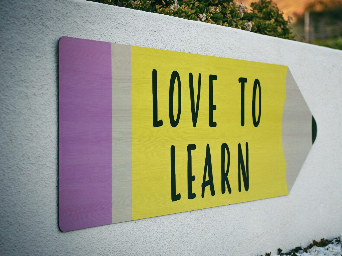 A pencil-shaped sign on a school wall reading Love to Learn
