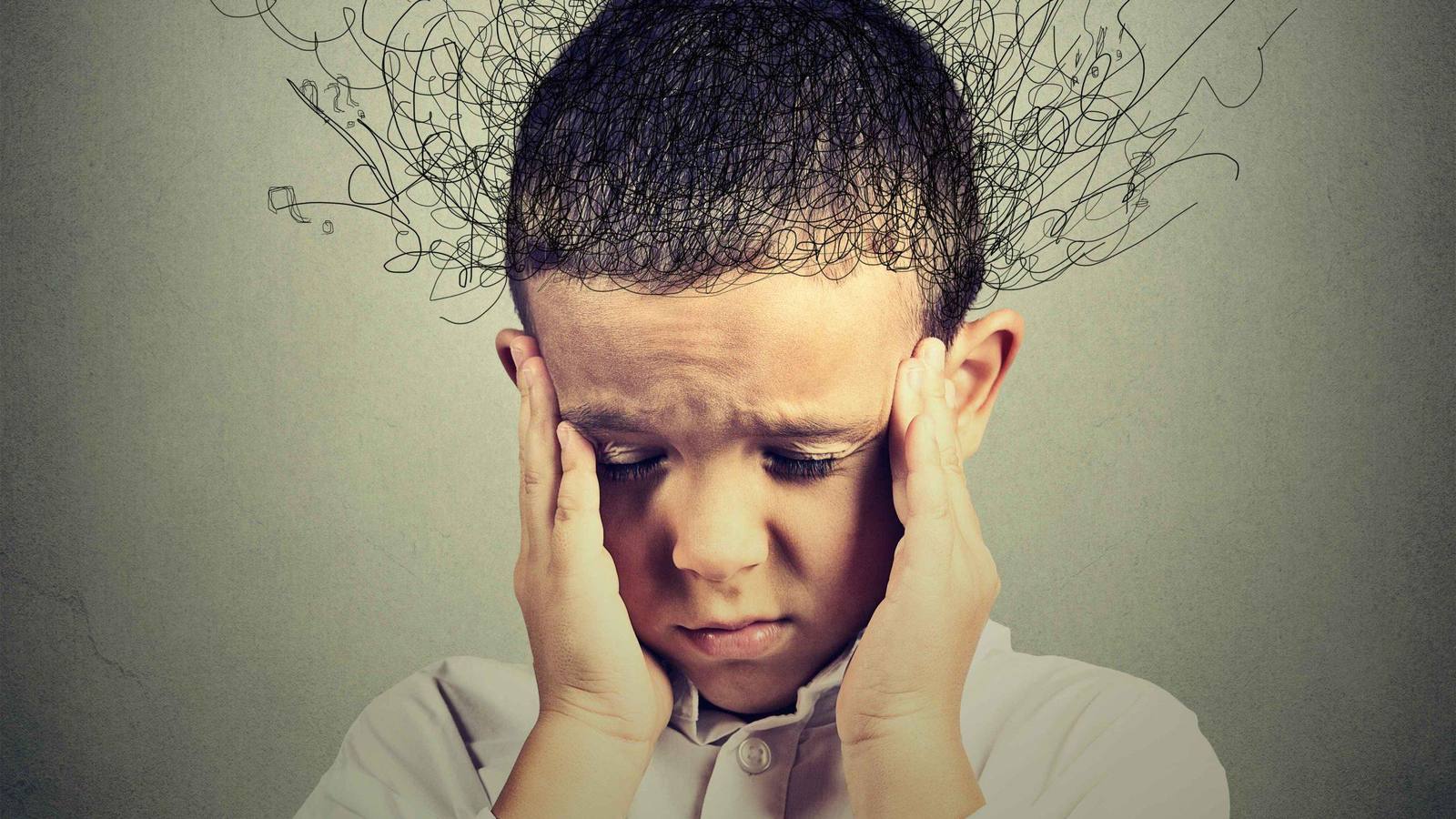A boy presses his hands to his temples while a tangle of scribbled lines rises from his head