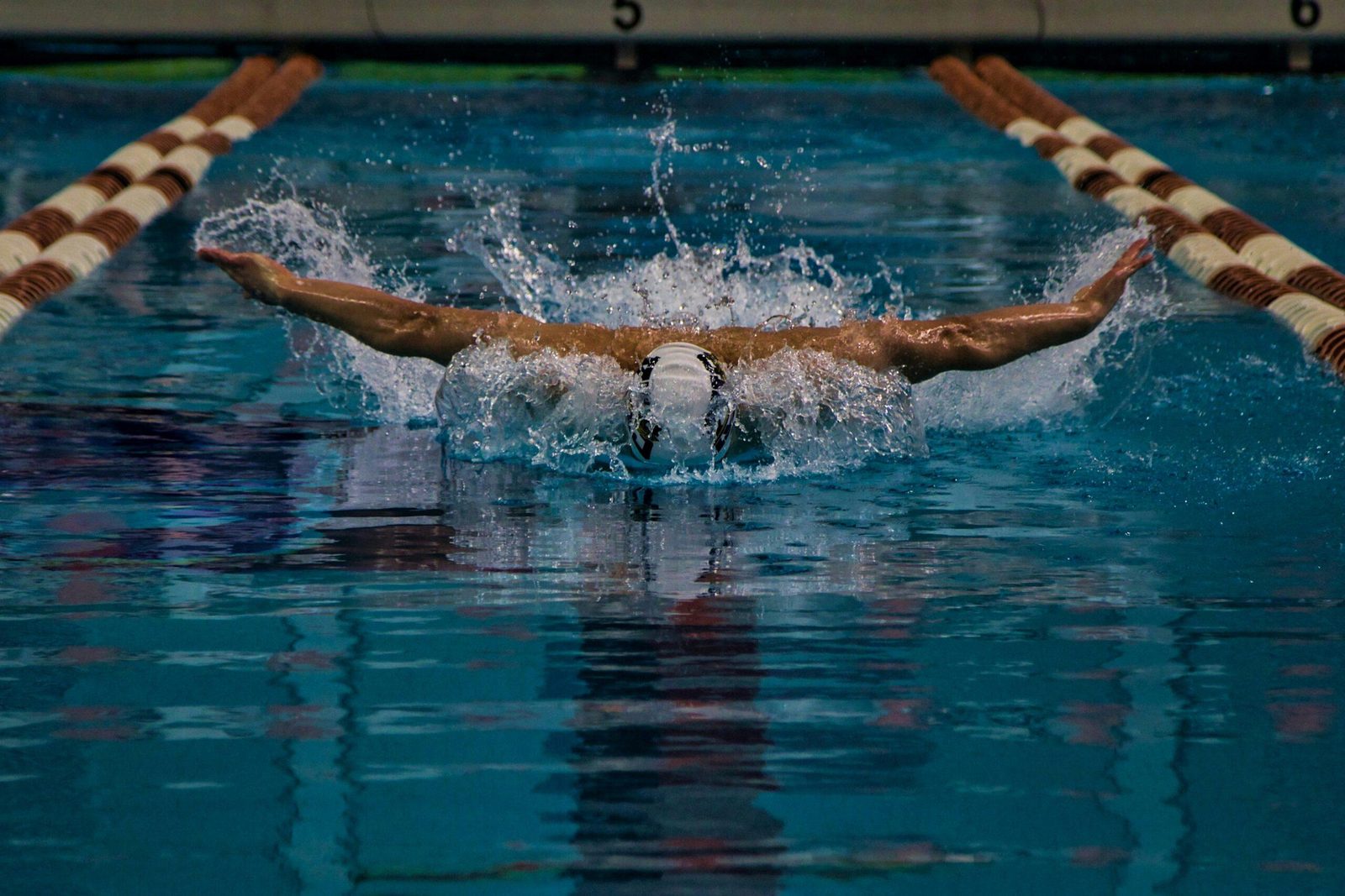 A swimmer bursts through the water mid butterfly stroke